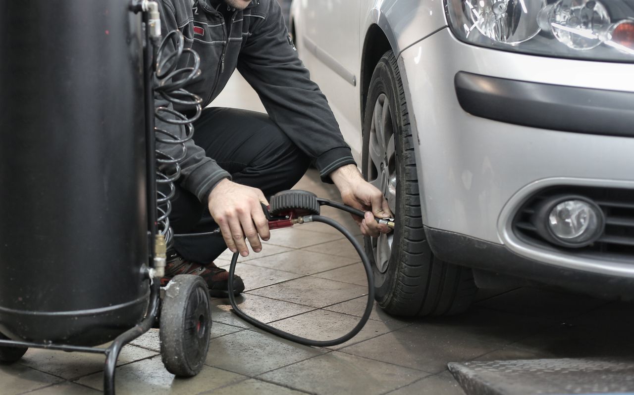 A mechanic working under the hood of a car in a busy auto repair shop